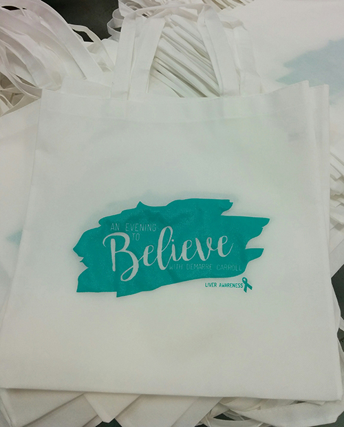 Charitable custom tote bags printed in white with custom design for giveaways.