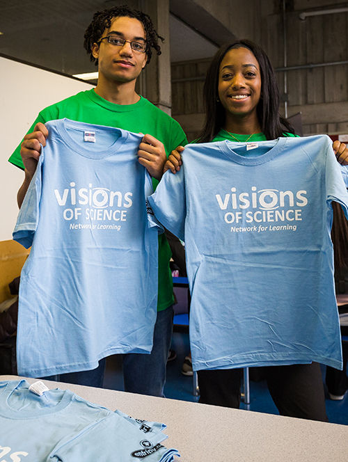 Youth giving away custom printed t-shirts from Vision of Science organization.