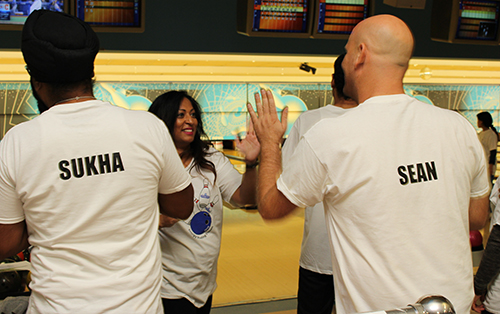 Entripy's employees wearing white custom t-shirts at bowling with their names personalized on the back.