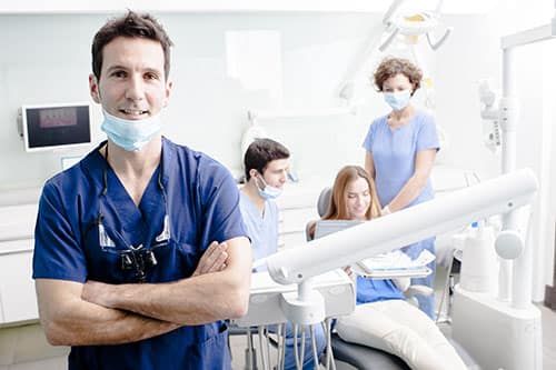 Dental patients and dentists in the office preparing tools wearing custom uniforms.