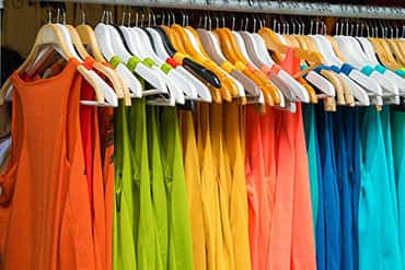 Colourful sleeveless t-shirts hanging, ready to be customized with design or logo.