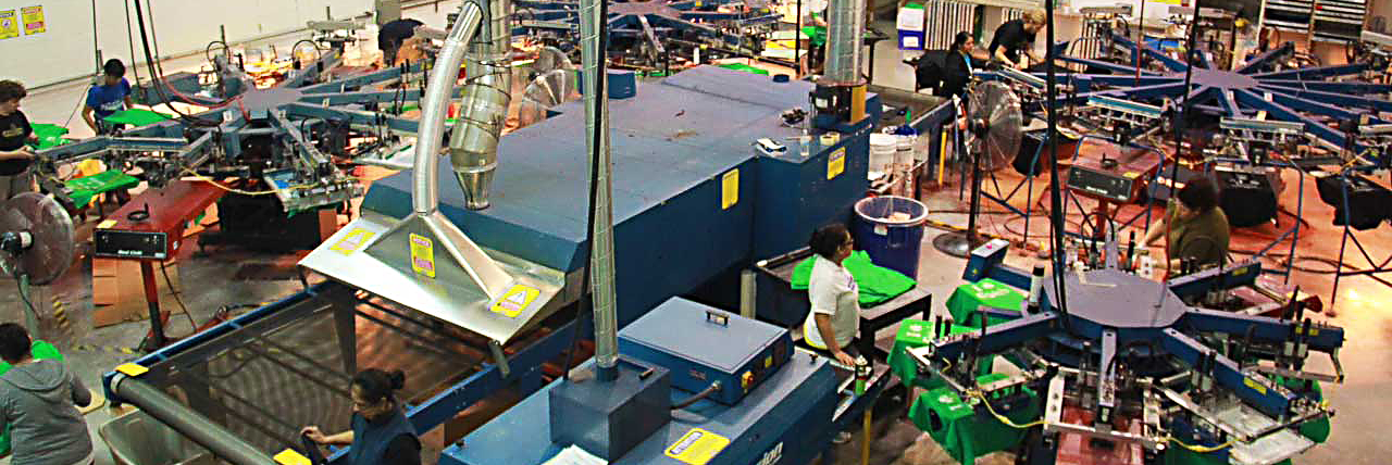 Screen-printing machines with Entripy employees printing custom t-shirts for client orders.