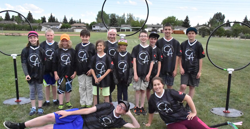 Group of youth Quidditch players wearing black custom jerseys with their school logo.