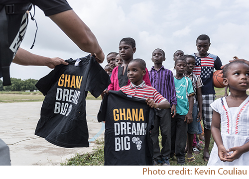 Volunteer members of Giants of Africa organization handing out custom printed t-shirts to children of Ghana.