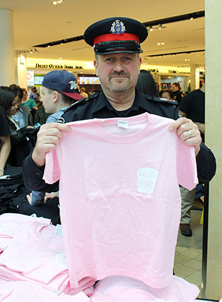 Cops for Cancer officer displaying a pink printed t-shirt with custom logo for supporters to purchase.