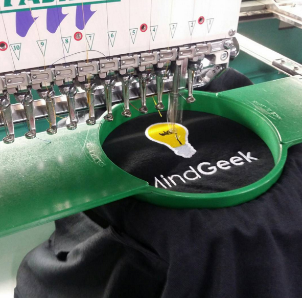 Embroidering machine creating a logo with a design on custom polo shirt.