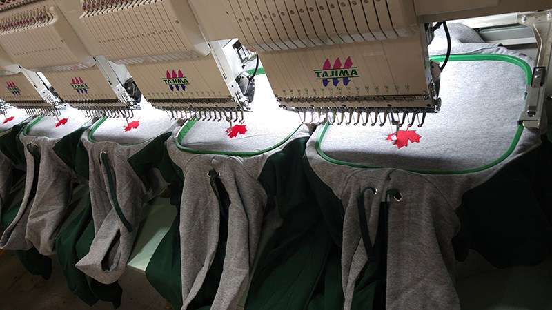 Custom hooded sweatshirt being embroidered with a Maple Leaf logo.