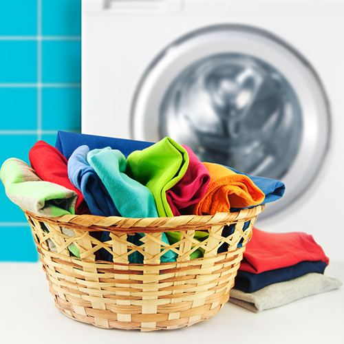 Washed bright coloured custom clothing in laundry basket.