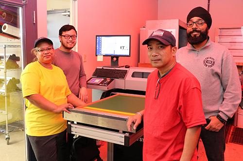 Entripy's pre-production team working on the new direct-to-screen machine for customer's custom apparel order.