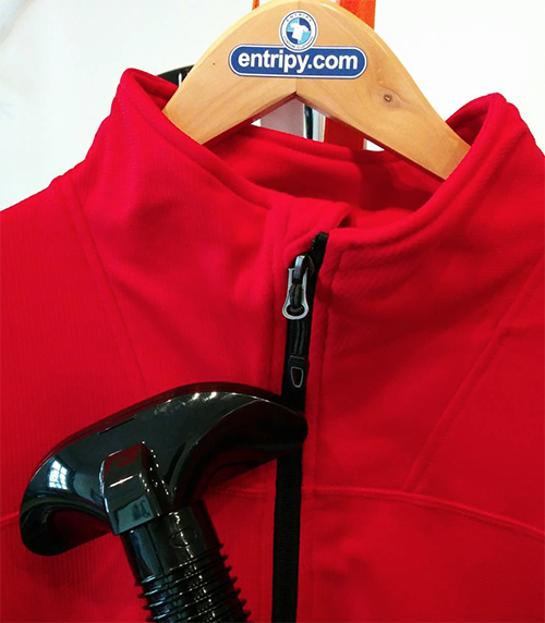 Red custom jacket being steamed to remove wrinkles before taking a picture of it to post online.