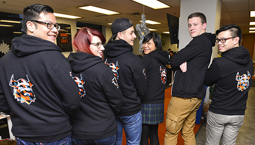 Diverse group posing wearing black custom hoodies with embroidered logo.