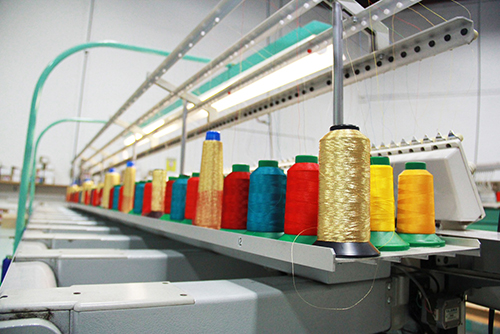 Colourful threads on top of embroidering machines for custom clothing orders.