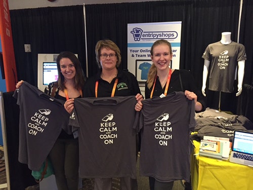 Customers holding black custom t-shirts at a trade show for EntripyShops.