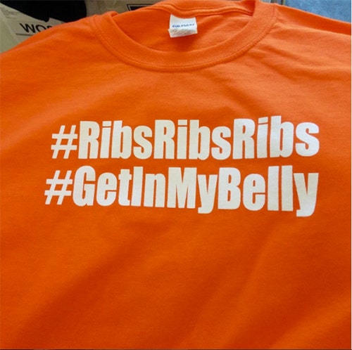 Hashtags printed on orange custom t-shirts for an outdoor food festival.